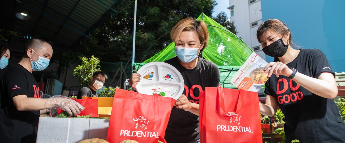 Prudential employee Ms Ariel Ong assembling a care pack consisting of fresh produce, a “Healthy Plate”, and a recipe card, together with her colleagues.